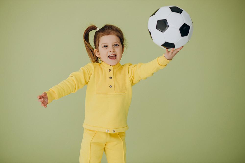Cute little girl with soccer ball in studio
